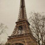 De Eiffeltoren in Parijs vanaf straatniveau, omringd door bomen