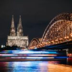 Hotel bij de kerstmarkt van Keulen: 8 hotels op loopafstand (2026) De verlichte Dom van Keulen en de Hohenzollernbrücke over de Rijn bij nacht