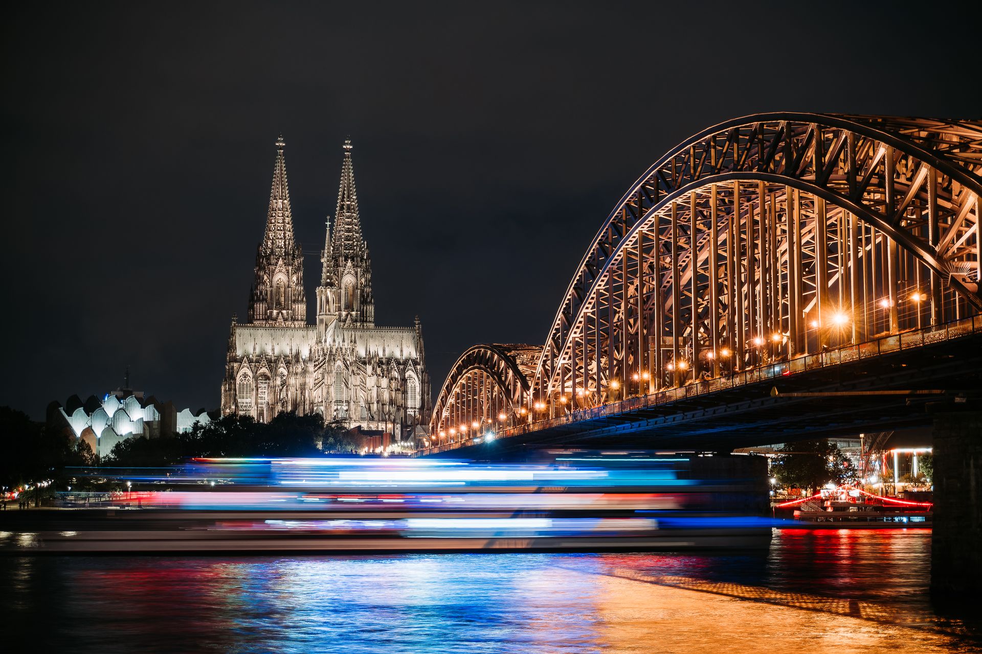 De verlichte Dom van Keulen en de Hohenzollernbrücke over de Rijn bij nacht