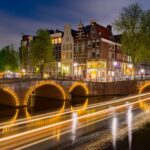 Amsterdamse gracht met verlichte bruggen en grachtenpanden bij nacht