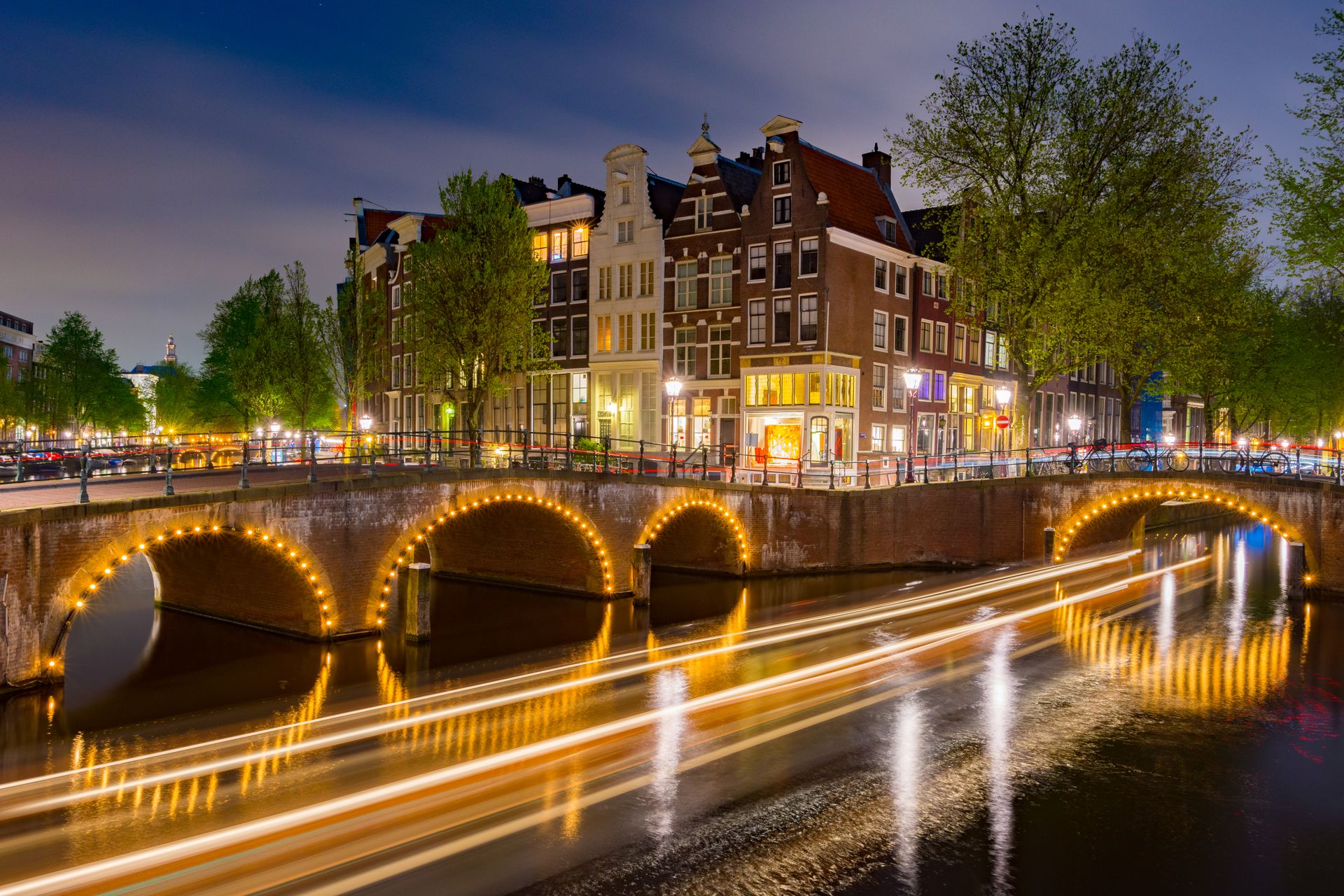 Amsterdamse gracht met verlichte bruggen en grachtenpanden bij nacht